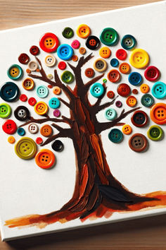 a tree made out of buttons sitting on top of a white canvas with an orange and yellow design