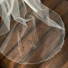 a veil with two hearts on it sitting on top of a wooden floor in front of a window