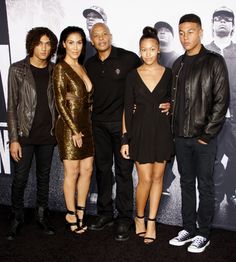 a group of people standing next to each other in front of a wall with a movie poster on it