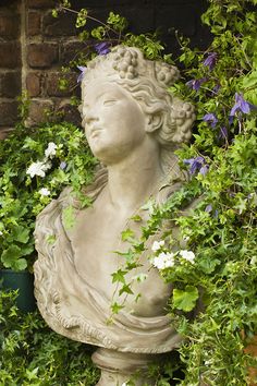 a statue is surrounded by plants and flowers