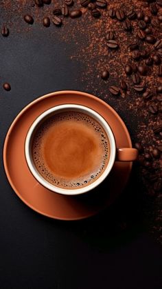 a cup of coffee sitting on top of a saucer next to some coffee beans