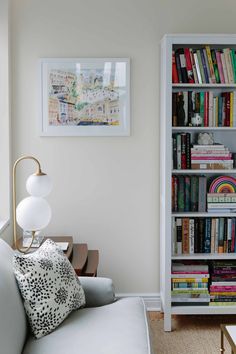 a living room filled with furniture and a book shelf next to a white couch in front of a window