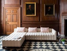 a living room with large wooden paneled walls and paintings on the wall behind it