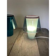 a table lamp sitting on top of a wooden floor next to a blue vase with a light in it