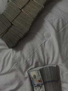 a stack of money sitting on top of a bed next to a pile of sticks