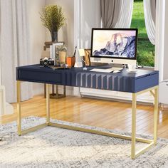 a desk with a computer on top of it in front of a window and a rug