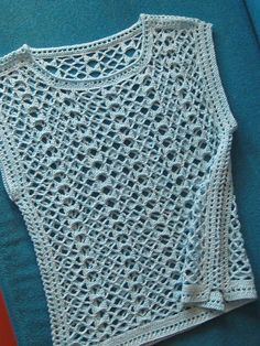 a white crocheted top on a blue surface