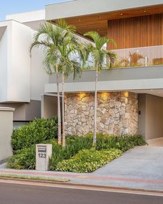 a modern home with palm trees and landscaping in front of the entrance to the house