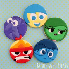 four decorated cookies in the shape of cartoon characters