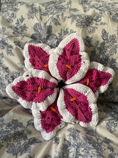 four crocheted flowers sitting on top of a bed