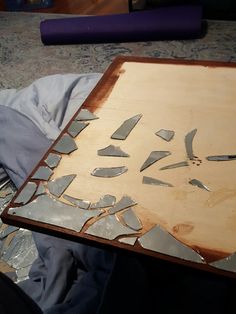 a wooden table topped with lots of broken pieces of glass on top of metal foil