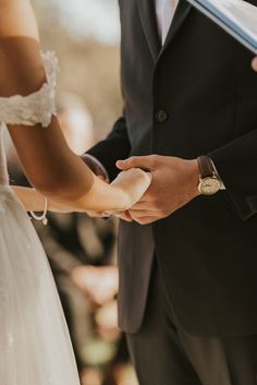 a bride and groom holding hands during their wedding ceremony