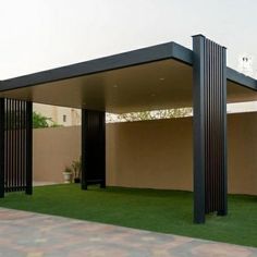 an outdoor covered area with green grass and black metal columns on the side of it