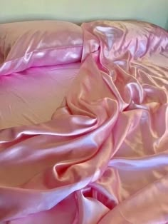 an unmade bed with pink sheets and pillows