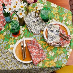 the table is set with two plates, silverware and napkins in front of flowers