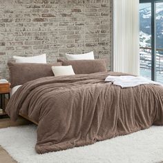 a bed in a bedroom with a brick wall and white fluffy rug on the floor