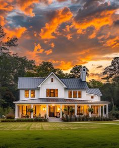 a large white house sitting on top of a lush green field under a cloudy sky