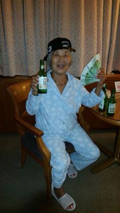 a man sitting in a chair holding two beer bottles