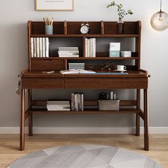 a wooden desk with books, magazines and other items on it in front of a gray wall