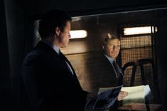 two men in suits are looking at papers