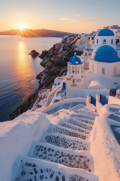 the sun is setting over some white buildings by the water with steps leading up to them