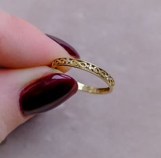 a woman's hand holding a gold ring