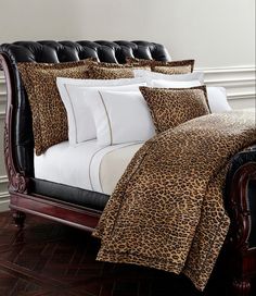 a leopard print comforter set on a bed with black leather headboard and foot board