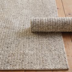 a close up of a rug on a wooden floor with a roll of fabric next to it