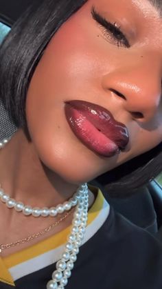 a woman with black hair wearing pearls and lipstick