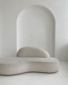 a white couch sitting in the middle of a room with arches on it's walls