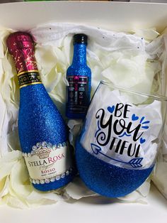 two bottles of wine in a box with white flowers and blue ribbon around the bottle