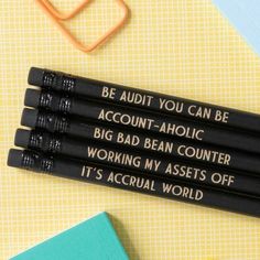 three black pencils with writing on them sitting next to some books and an eraser