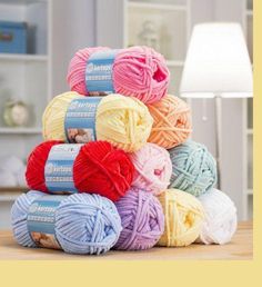 several balls of yarn sitting on top of a wooden table next to a white lamp