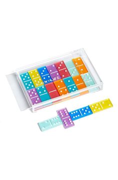 an assortment of colored dominos in a plastic case on a white background with one missing