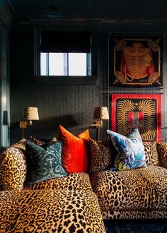 a leopard print couch with colorful pillows and lamps