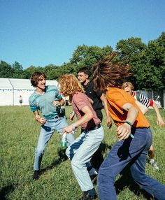 a group of young people playing with a frisbee in the grass on a sunny day