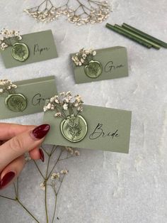 a hand holding some cards with flowers on them and writing the name of each card