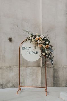 a sign with flowers on it sitting in front of a wall