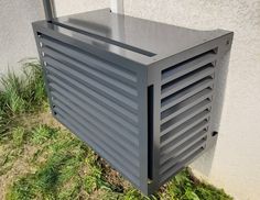 a metal box sitting in the grass next to a building