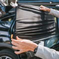 a person holding a piece of luggage in front of a car with the door open