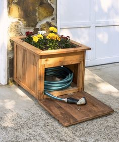 a planter box with flowers in it and a hose connected to the ground below