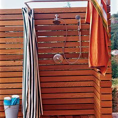 an outdoor shower with wooden slatted walls and towels hanging on the wall next to it