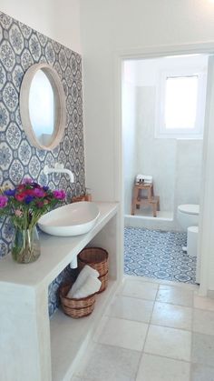 a white sink sitting under a bathroom mirror next to a toilet in a bathroom with blue and white tiles on the walls