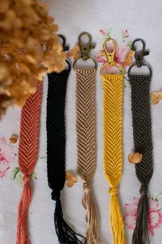 five different colored tassels are lined up on a white tablecloth with flowers