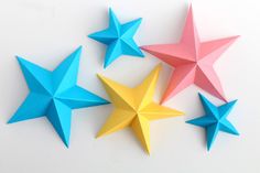 five origami stars are arranged on a white surface, each with different colors