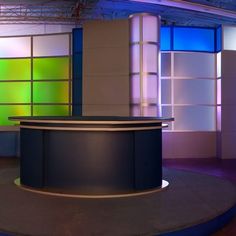 an empty television studio with colorful lights on the walls and behind it is a curved counter