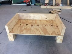 a wooden bench sitting on top of a floor next to a pile of wood planks