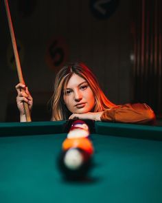 a woman leaning over a pool table with a cue in her hand and a billiard stick