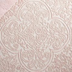 a pink and white quilted bed spread with an intricate design on the bottom half