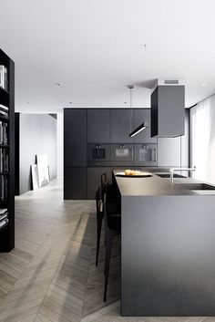 a kitchen with black cabinets and an island in the middle is seen from across the room